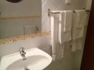 a white bathroom with a sink and towels at Patio das Margaridas in Óbidos