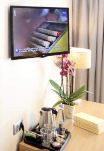 een tv aan de muur met een dienblad op een bureau bij Trinite Hotel in La Trinité-sur-Mer