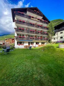 a large apartment building with a green lawn in front of it at Hotel Adonis in Zermatt