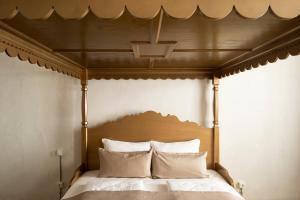 ein hölzernes Himmelbett mit weißen Kissen darauf in der Unterkunft rössl bianco b&b&b in Meran