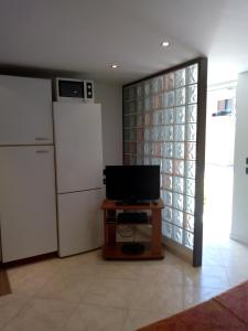a kitchen with a refrigerator and a tv and a table at Apartment with a Secret and Romantic Park in Venice