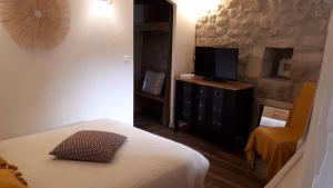 1 dormitorio con cama y vestidor con TV en Gîte de village, en La Garde-Adhémar