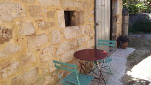 una mesa y sillas junto a una pared de piedra en Gîte de village, en La Garde-Adhémar