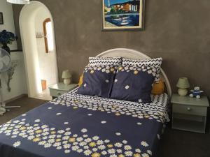 1 cama con edredón azul y flores amarillas y blancas en La Inna, en Cagnes-sur-Mer