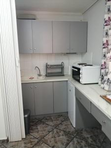 una cucina con armadi bianchi, lavandino e forno a microonde di Sunny garden studio ad Atene