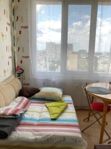 a bed in a room with a table and windows at Airport Apartment in Sofia