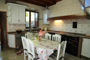 una cocina con mesa con sillas blancas y una cocina con mesa en A Casa Da Asturiana, en Sotomayor