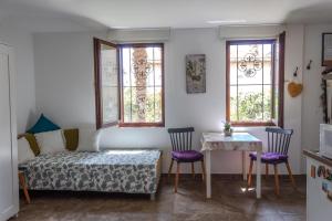 a bedroom with a bed and a table and windows at Little garden house in Rijeka