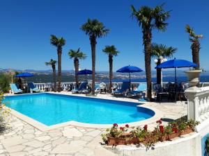a swimming pool with palm trees and blue umbrellas at Apartments Darijana in Opatija