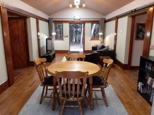 een woonkamer met een houten tafel en stoelen bij Wyldwood Lodge in Cheadle
