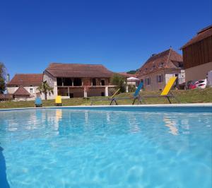 a swimming pool with two chairs and a house at Gites chez Antonin in Tour-de-Faure