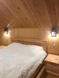 a bed in a wooden room with two lights at Ялинка in Migovo