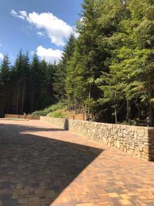 a brick road with a stone wall and trees at Ялинка in Migovo