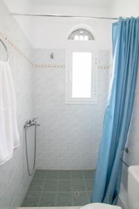a bathroom with a shower with a blue shower curtain at Porto Vidali in Agios Ioannis