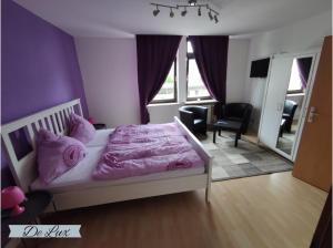 una camera da letto con letto e lenzuola e cuscini rosa di De Lux Gästehaus Völklingen a Völklingen