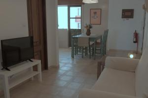 a living room with a television and a table with chairs at Flat Ocean View T2 in Monte Gordo