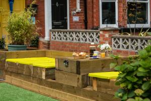 patio z żółtymi stołami i ławkami przed domem w obiekcie Chomley holiday flats w Scarborough