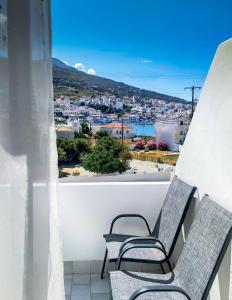 a balcony with two chairs and a view of a city at Blue Era Apartments in Batsi