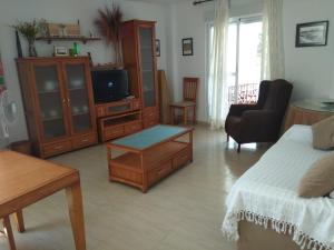 een woonkamer met een bed en een televisie bij Apartamento La Rotonda C-116 in Conil de la Frontera