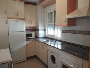 een keuken met een witte koelkast en een vaatwasser bij Apartamento La Rotonda C-116 in Conil de la Frontera