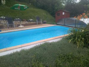 a large blue swimming pool with an umbrella at Penzion U Slunce in Jaroměř
