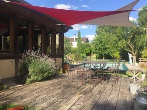 een terras met een tafel en stoelen en een parasol bij le Clos de la Livre in Fontaine-sur-Ay