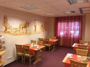 a dining room with tables and chairs and paintings on the walls at Hotel Gasthof Familie Czepl in Ernsthofen