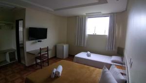 a small room with a bed and a television at Hotel Litoral in Aracaju
