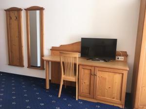 Cette chambre comprend un bureau avec une télévision et une chaise. dans l'établissement Hotel Gasthof Familie Czepl, à Ernsthofen