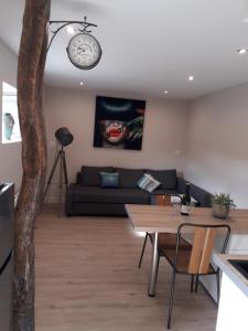 a living room with a couch and a clock on the wall at Appartement cosy au coeur du Beaujolais in Saint-Lager