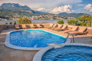 a swimming pool with chairs and a view of the mountains at Apartments Obala - Katić in Herceg-Novi