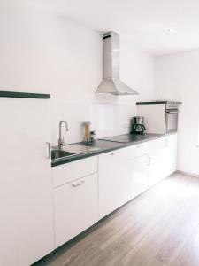 a white kitchen with white cabinets and a sink at Klärchen's Stube in Telgte