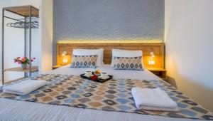 a bed with two pillows and a tray of food on it at Linda Apartments Platanias in Plataniás