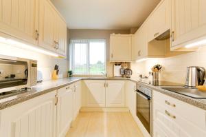 a kitchen with white cabinets and a window at Seaview - Cheviot Court in Broadstairs