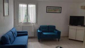 Treignac的住宿－Hôtel du Lac，客厅配有2把蓝色椅子和电视
