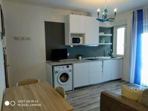 a kitchen with a washing machine and a table at Mandracchio Central Apartment in Grado