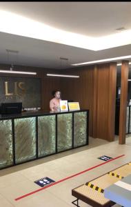 un hombre está parado en un mostrador en un edificio en Lis Hotel en Teresina