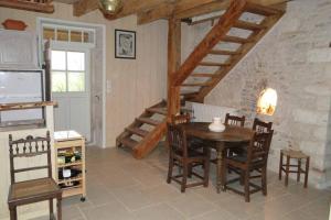 a dining room with a table and chairs and a staircase at Gîte La Garauderie in LʼÎle-dʼElle