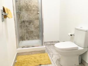 La salle de bains est pourvue d'une douche, de toilettes et d'un tapis. dans l'établissement Grace Apartments - Living Stone 1, à Kent