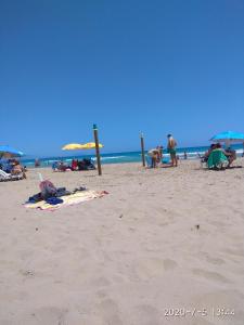 eine Gruppe von Menschen am Strand mit Sonnenschirmen in der Unterkunft Piso Vacacional in San Juan de Alicante