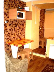 uma cozinha com uma mesa, 2 bancos e um micro-ondas em Небольшая студия, пр. Центральный, 148, 1этаж-9этажного дома, WI-FI, 2 дивана и 2 кресла em Nikolayev