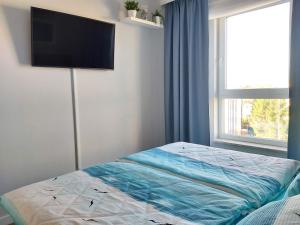 a bedroom with a bed with a flat screen tv on the wall at Bel Mare Sztorm in Międzyzdroje