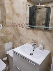 ein Badezimmer mit einem weißen Waschbecken und einem Spiegel in der Unterkunft Apartament Platynowy w Centrum Miasta in Częstochowa
