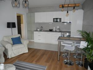 a kitchen with white cabinets and a table and a chair at Apartament Platynowy w Centrum Miasta in Częstochowa