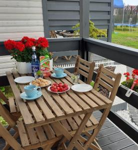 a wooden table with food and flowers on a porch at Błękitna Laguna 600m od morza in Rusinowo