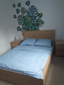 a bedroom with a bed with blue sheets and a plant wall at Apartament nr 19 in Dziwnówek