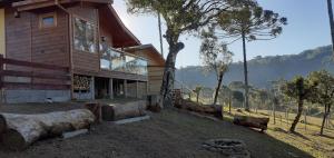 a wooden house with logs in front of it at Chalé Bienz - Hospedagem Rural in Urubici