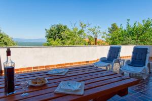 - une table en bois avec 2 chaises bleues et une bouteille de vin dans l'établissement Apartment Šoštarić, à Krk