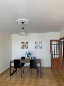 a dining room table with chairs and a vase of flowers at Piso en el malecón de Riveira con vistas a las Rias Baixas. Ideal para familias. 140m in Ribeira