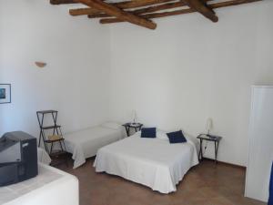 a white room with two beds and a tv at Da Marusca in Santa Marina Salina